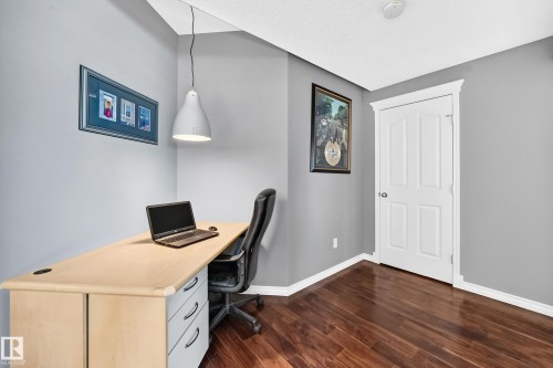 Dark wood-finish flooring with crisp white baseboards - 12720 Hudson Way Nw, Edmonton, AB - Indoor Photo Showing Office