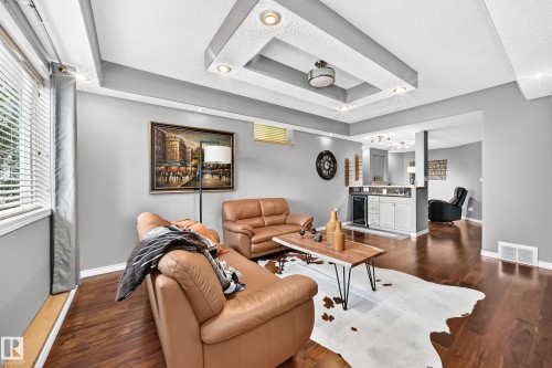 Recessed lighting and a decorative tray ceiling complement the wood-finish flooring - 12720 Hudson Way Nw, Edmonton, AB - Indoor Photo Showing Living Room