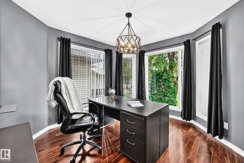 Office space featuring a bay window with multiple large windows, rich wood-finish flooring, and a modern geometric chandelier - 12720 Hudson Way Nw, Edmonton, AB - Indoor Photo Showing Office