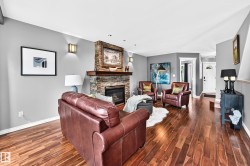Spacious living area featuring wood-finish flooring, a stone-clad fireplace with a wood mantel, and recessed lighting - 
