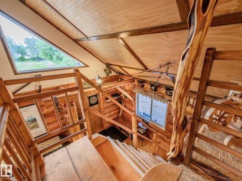 Multi-level interior featuring a unique triangular window, wood-finish sloped ceilings, natural log walls, and wood railings with decorative carved elements - 58227 Range Rd 70 A, Rural St. Paul County, AB -  Photo Showing Other Room