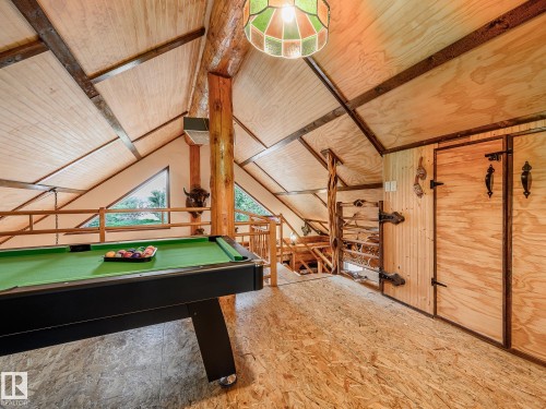 Spacious loft area featuring a pool table, sloped wood-paneled ceilings, natural wood structural beams, and triangular windows - 58227 Range Rd 70 A, Rural St. Paul County, AB - Indoor Photo Showing Other Room