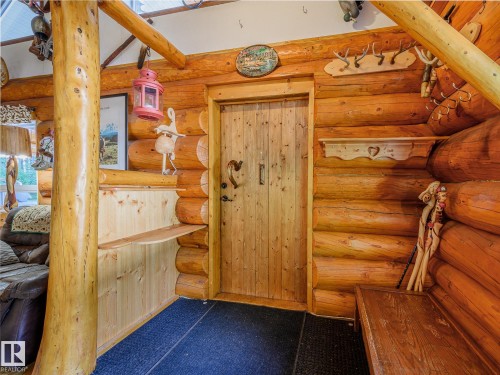 Interior featuring natural log walls, a solid wood door, and a built-in wooden bench - 58227 Range Rd 70 A, Rural St. Paul County, AB - Indoor Photo Showing Other Room