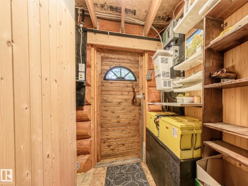 Interior space featuring a wooden plank door with an arched window, log wall construction, and exposed wood ceiling joists - 58227 Range Rd 70 A, Rural St. Paul County, AB - Indoor Photo Showing Other Room