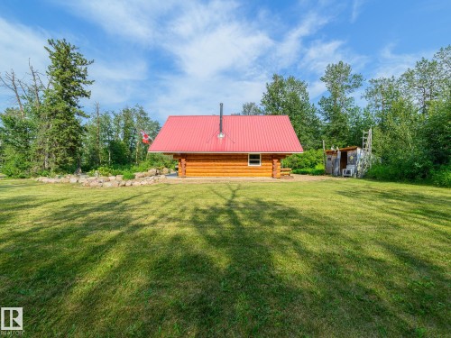Log cabin with a red metal roof and a stone-lined garden bed - 58227 Range Rd 70 A, Rural St. Paul County, AB - Outdoor