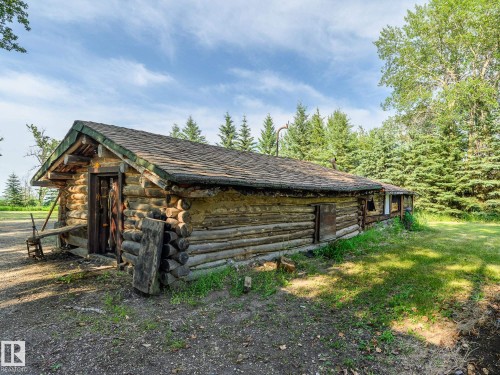 Rustic log cabin exterior with a shingled roof, featuring exposed log construction and a natural wood door - 58227 Range Rd 70 A, Rural St. Paul County, AB - Outdoor