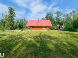 Log cabin with a red metal roof and a stone-lined garden bed - 