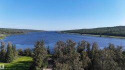 Expansive waterfront property featuring a large body of water, dense tree lines, and a clear sky - 