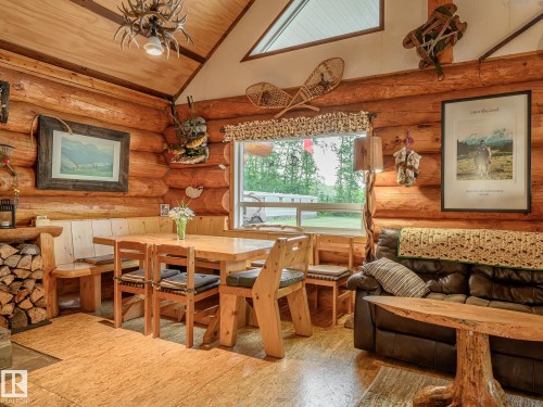 Interior featuring log wall construction, natural wood flooring, a built-in wood bench with dining table, large window, and vaulted ceiling - 58227 Range Rd 70 A, Rural St. Paul County, AB - Indoor Photo Showing Dining Room