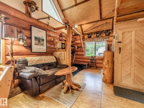 Wood-paneled interior featuring log walls, wood-finish flooring, and exposed wood ceiling beams - 58227 Range Rd 70 A, Rural St. Paul County, AB - Indoor