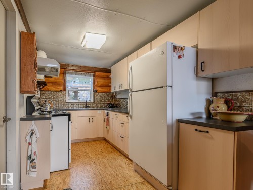 Functional kitchen featuring wood-finish flooring, ample cabinetry, a white refrigerator, a white range, and a window with natural light - 58227 Range Rd 70 A, Rural St. Paul County, AB - Indoor Photo Showing Kitchen