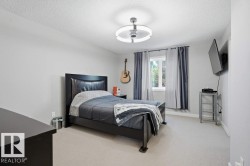 Spacious room featuring light-colored carpeting, a contemporary ceiling light fixture, and a window with neutral-toned drapes - 