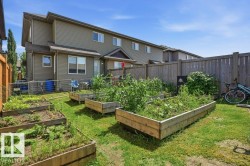 Private backyard featuring multiple raised garden beds, a wooden privacy fence, and a grass lawn - 