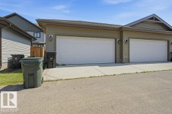 Attached two-car garage featuring panel-style doors, siding exterior, and exterior lighting fixtures - 