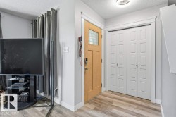 Entryway featuring a natural wood-finish door with frosted glass insert, wood-finish flooring, white bi-fold closet doors with raised panel details, and a flush-mount ceiling light - 