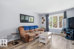 Bright living area featuring wood-finish flooring and a large multi-pane window - 