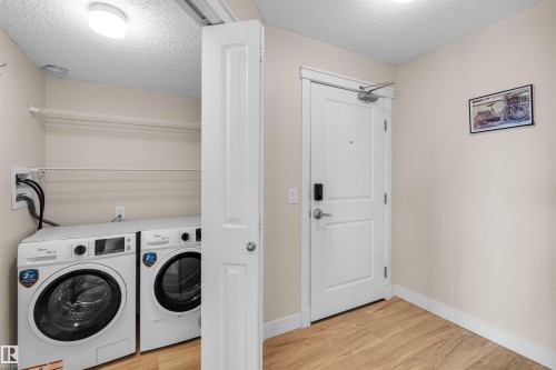 Dedicated laundry area with front-loading washer and dryer, complemented by wire shelving for storage - #317 3719 Whitelaw Ln Nw, Edmonton, AB - Indoor Photo Showing Laundry Room
