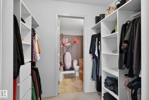 Walk-in closet featuring white built-in shelving, hanging rods, and integrated drawers - 423 2430 Guardian Road, Edmonton, AB - Indoor With Storage