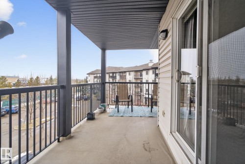 Private balcony featuring a concrete floor, black metal railing, and a sliding glass door with screen - 423 2430 Guardian Road, Edmonton, AB - Outdoor With Balcony With Exterior