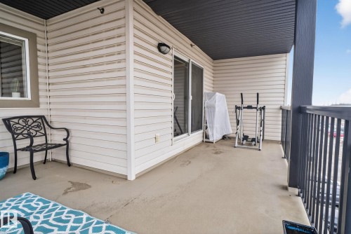 Outdoor balcony featuring a concrete surface, white horizontal siding, and a dark grey ceiling - 423 2430 Guardian Road, Edmonton, AB - Outdoor With Exterior