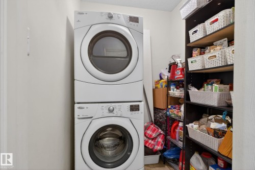 Dedicated laundry area featuring a white stacked washer and dryer unit - 423 2430 Guardian Road, Edmonton, AB - Indoor Photo Showing Laundry Room