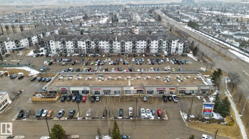 Commercial property featuring multiple retail storefronts, extensive surface parking, and a prominent roadside sign - 423 2430 Guardian Road, Edmonton, AB - Outdoor With View