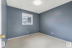Room featuring gray-blue painted walls, light-colored carpet flooring, a single window with blinds, and a ceiling-mounted light fixture - 