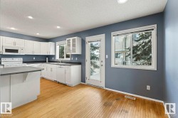Kitchen featuring white cabinetry, a kitchen island, recessed lighting, wood-finish flooring, and a glass-paneled exterior door - 