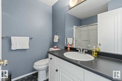Bathroom featuring a white vanity with dark countertop, an integrated sink, and a mirrored medicine cabinet - 