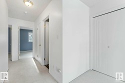 Hallway with light-colored carpeting, white painted walls, and multiple doorways - 
