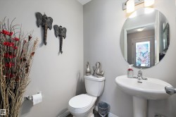 Powder room featuring a pedestal sink, round wall-mounted mirror, and overhead vanity lighting - 