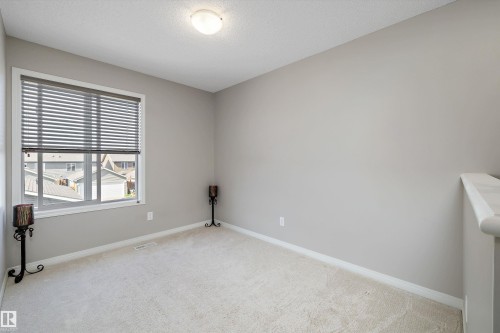 Neutral-toned room featuring a large window with horizontal blinds, providing natural illumination - 4688 Crabapple Run Sw, Edmonton, AB - Indoor Photo Showing Other Room
