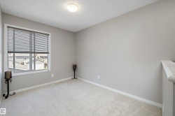 Neutral-toned room featuring a large window with horizontal blinds, providing natural illumination - 