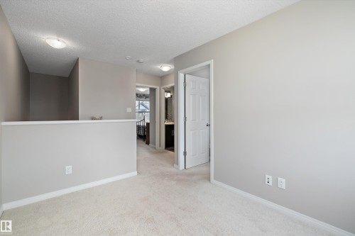 Carpeted upper-level hall featuring a half-wall railing, overhead flush mount lighting, and neutral wall tones - 4688 Crabapple Run Sw, Edmonton, AB - Indoor Photo Showing Other Room