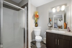 Bathroom featuring a glass-enclosed shower, a vanity with a built-in sink, a large mirror, and tiled flooring - 