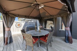 Expansive wood deck featuring a covered gazebo with string lighting - 