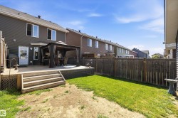 Expansive backyard featuring a wood deck with steps, a privacy fence, and a green lawn area - 