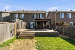 Expansive backyard featuring a large wooden deck with integrated steps, a privacy fence, and a spacious lawn area - 