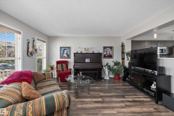 Spacious living area featuring wood-finish flooring, light grey walls, and ample natural light from multiple windows - 
