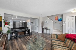 Open-concept living space featuring wood-finish flooring, a built-in electric fireplace, and light grey wall paint - 