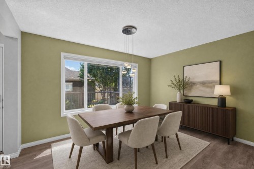 Dining space featuring wood-finish flooring, a contemporary pendant light fixture, a wide window with white trim, and a built-in dark wood sideboard - 3139 Carpenter Landing Sw, Edmonton, AB - Indoor Photo Showing Dining Room