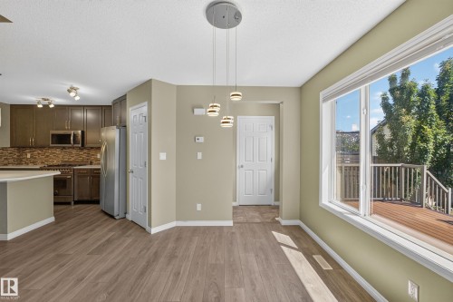 Open-concept living space featuring wood-finish flooring, a large window, contemporary pendant lighting, recessed ceiling lights, and a kitchen with stainless steel appliances - 3139 Carpenter Landing Sw, Edmonton, AB - Indoor Photo Showing Kitchen With Upgraded Kitchen