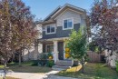 Two-story residence featuring light gray shingle siding, dark green horizontal siding, a covered front porch with white railings, and a bright yellow front door - 3139 Carpenter Landing Sw, Edmonton, AB  - Outdoor 