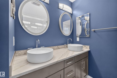 Contemporary double vanity featuring vessel sinks, polished chrome hardware, an integrated backsplash, and a patterned tile accent - 3139 Carpenter Landing Sw, Edmonton, AB - Indoor Photo Showing Bathroom