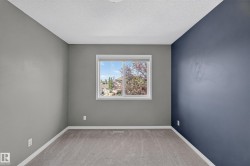 Carpeted room featuring a single window, white baseboards, and a textured ceiling - 