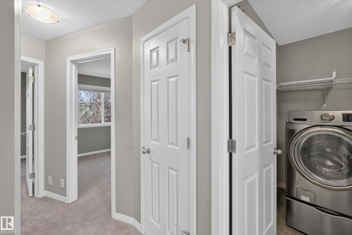 Dedicated laundry area featuring a front-loading washing machine, wire shelving, and wood-finish flooring - 3139 Carpenter Landing Sw, Edmonton, AB - Indoor Photo Showing Laundry Room