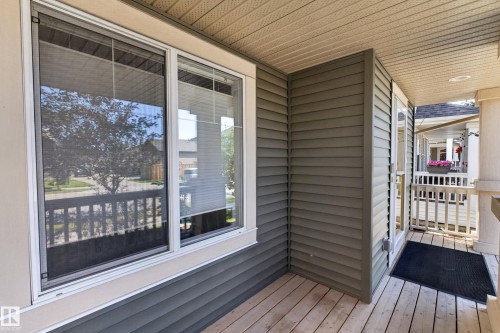 Covered front porch featuring wood-finish flooring, white railing, and grey horizontal siding - 3139 Carpenter Landing Sw, Edmonton, AB - Outdoor With Deck Patio Veranda With Exterior
