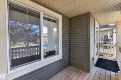 Covered front porch featuring wood-finish flooring, white railing, and grey horizontal siding - 
