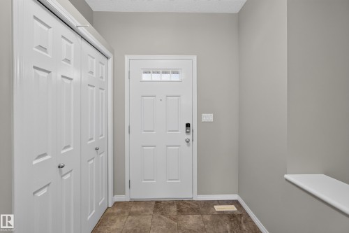 Entryway featuring a paneled door with transom window, tile flooring, and integrated bi-fold closet doors - 3139 Carpenter Landing Sw, Edmonton, AB - Indoor Photo Showing Other Room