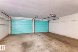 Two turquoise sectional garage doors within an interior garage space featuring a concrete floor and white painted walls - 